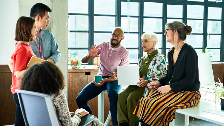 Meeting in an open plan office attended by a range of ethic backgrounds