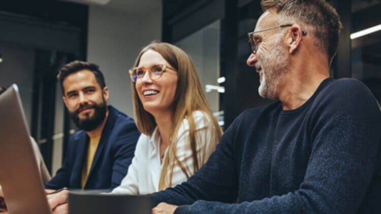 Successful group of businesspeople having a briefing in a boardroom. Happy businesspeople smiling while working together in a modern workplace. Diverse business colleagues collaborating on a project.