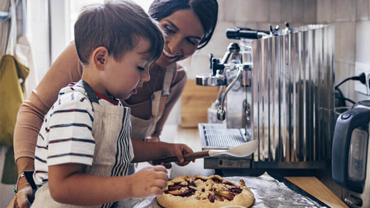 Mother helping her son make a pie in the kitchen