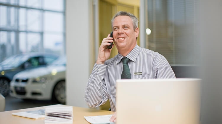 A male employee in a car showroom answers the phone