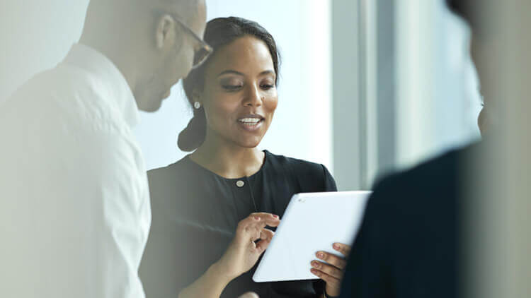 Business woman using a tablet device with colleagues in the office