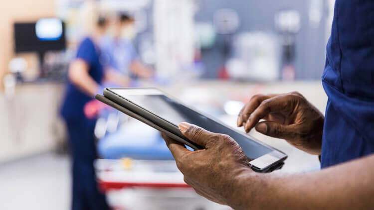 Medical professional using a mobile device stood in a hospital