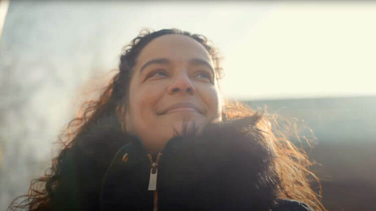 Woman wearing a black coat, looking optimistic with a smile on her face